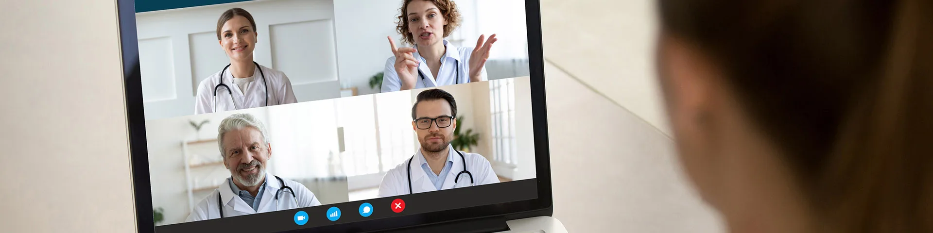 doctor looking at an open laptop screen that is displaying video call participants.