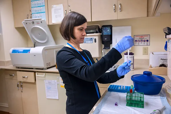 Researching in a clinical research center fulling a sample with a syringe 