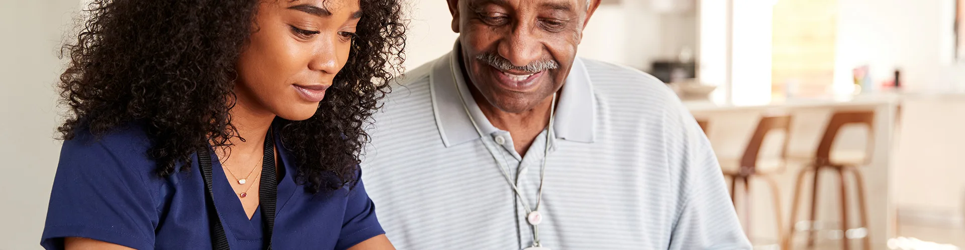 Young female provider reviewing paper work with an elderly male patient.