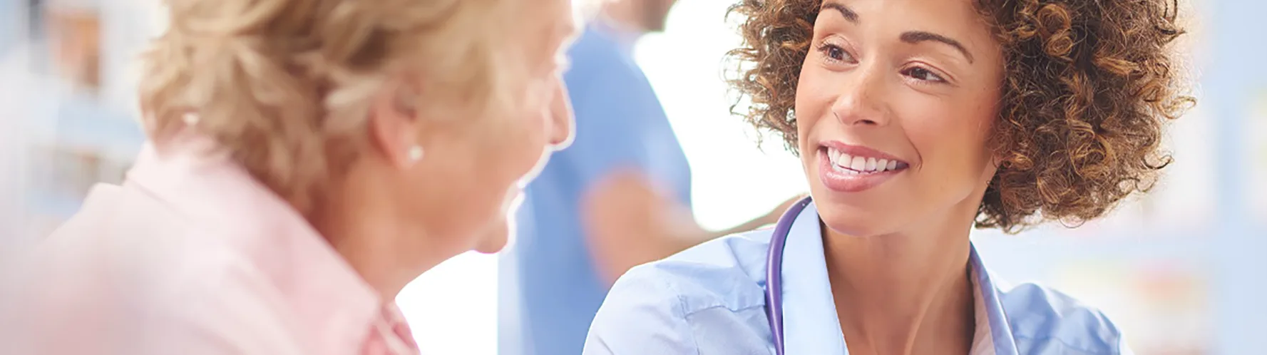 Side view of an elderly female patient interacting with a smiling medical professional.