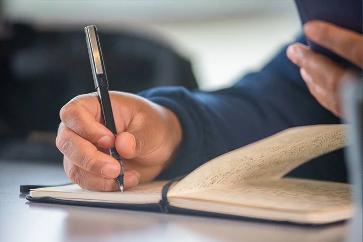 Penn Stater writing on notepad