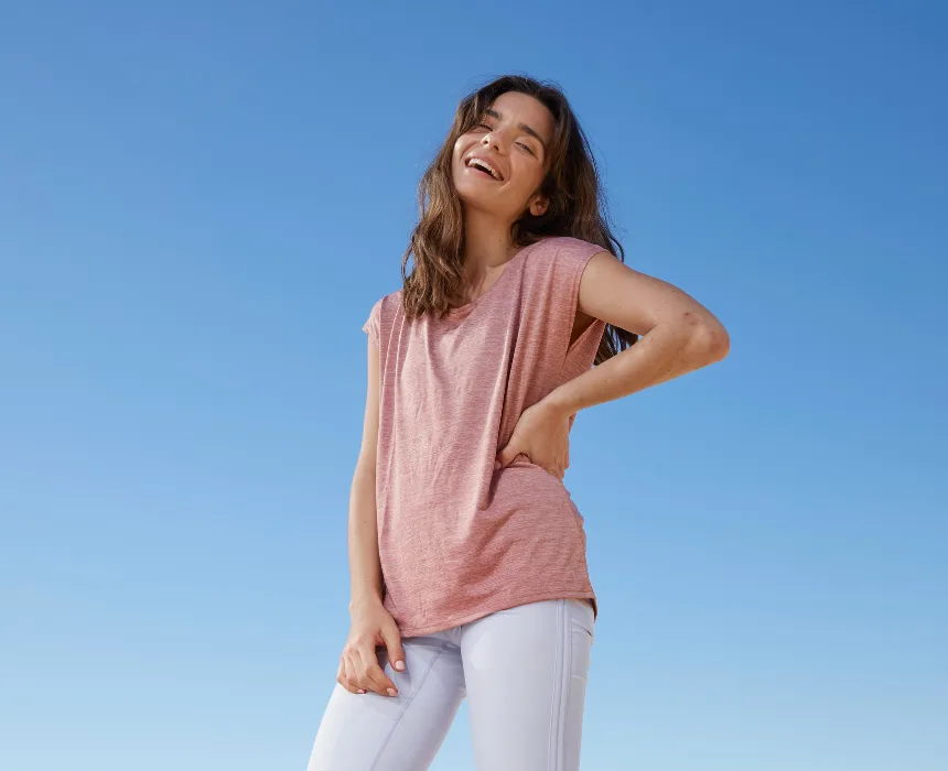 Young woman laughing beneath a clear sky