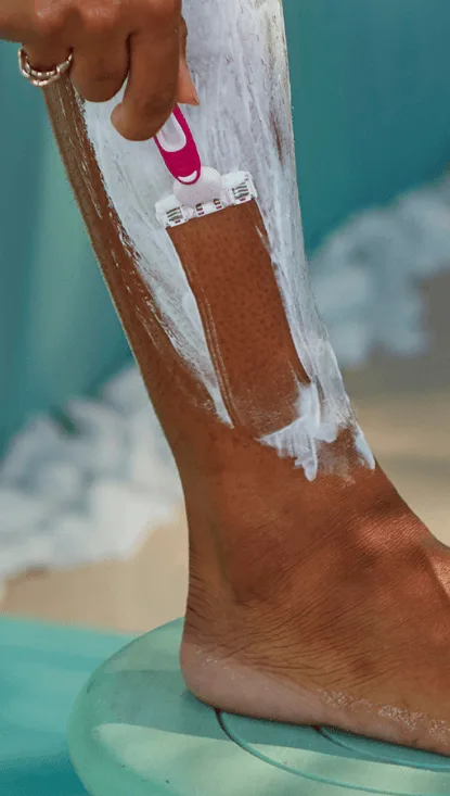 Woman shaving her creamed leg