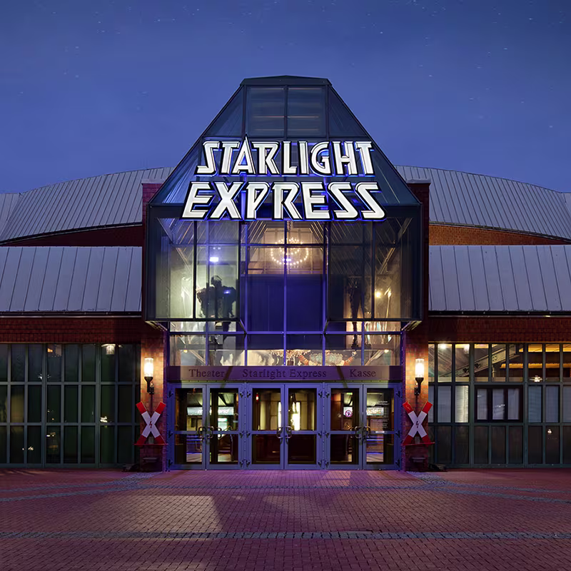 Beleuchteter Eingang des Starlight Express Theater in Bochum mit dem Schriftzug der Show in der Abenddämmerung