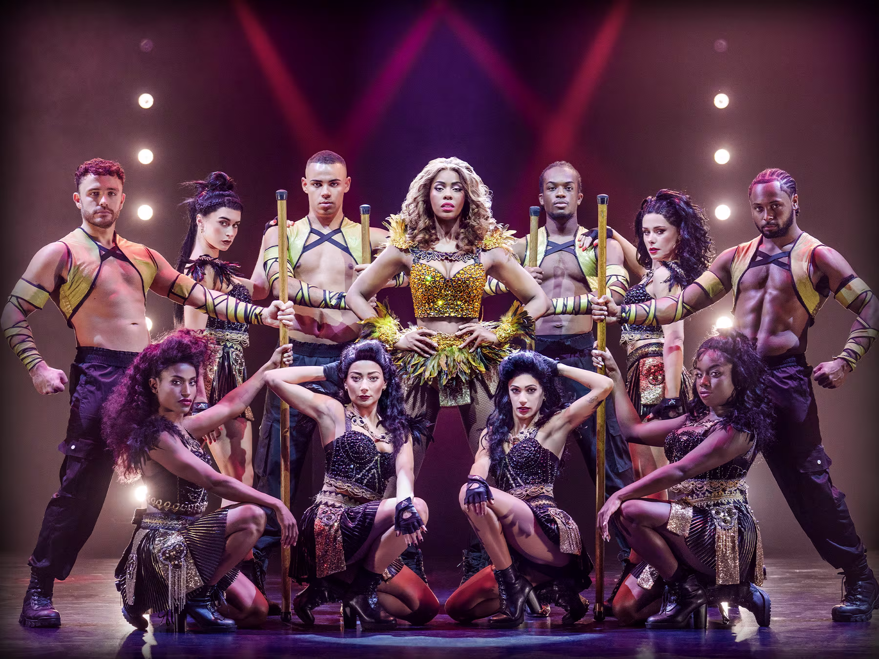 "The Bodyguard – The Musical": eine Gruppe von Männern und Frauen posiert auf einer beleuchteten Bühne. 