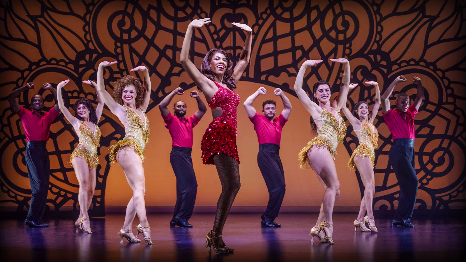 "The Bodyguard – The Musical": Bühne mit Tänzer*innen in rot-schwarzen und goldenen Outfits, die tanzen