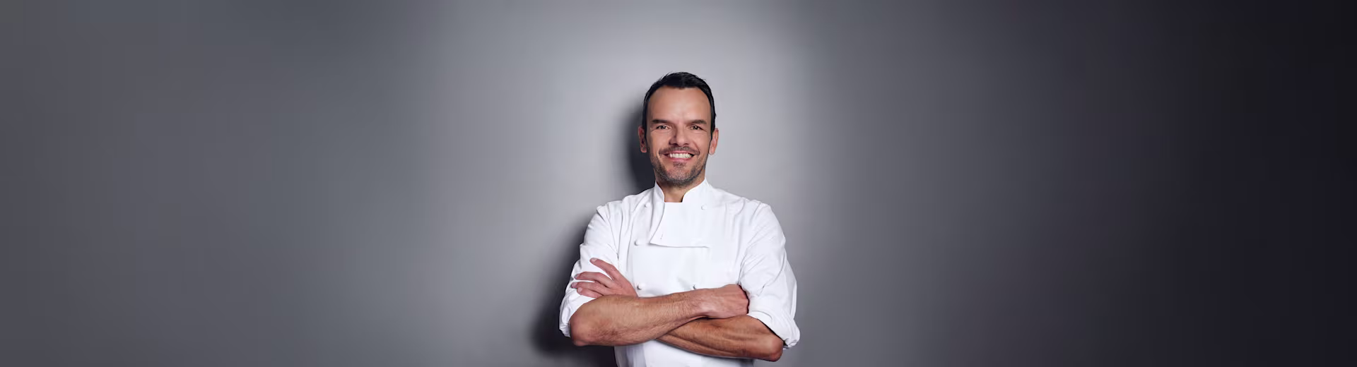 Steffen Henssler vor grauer Wand