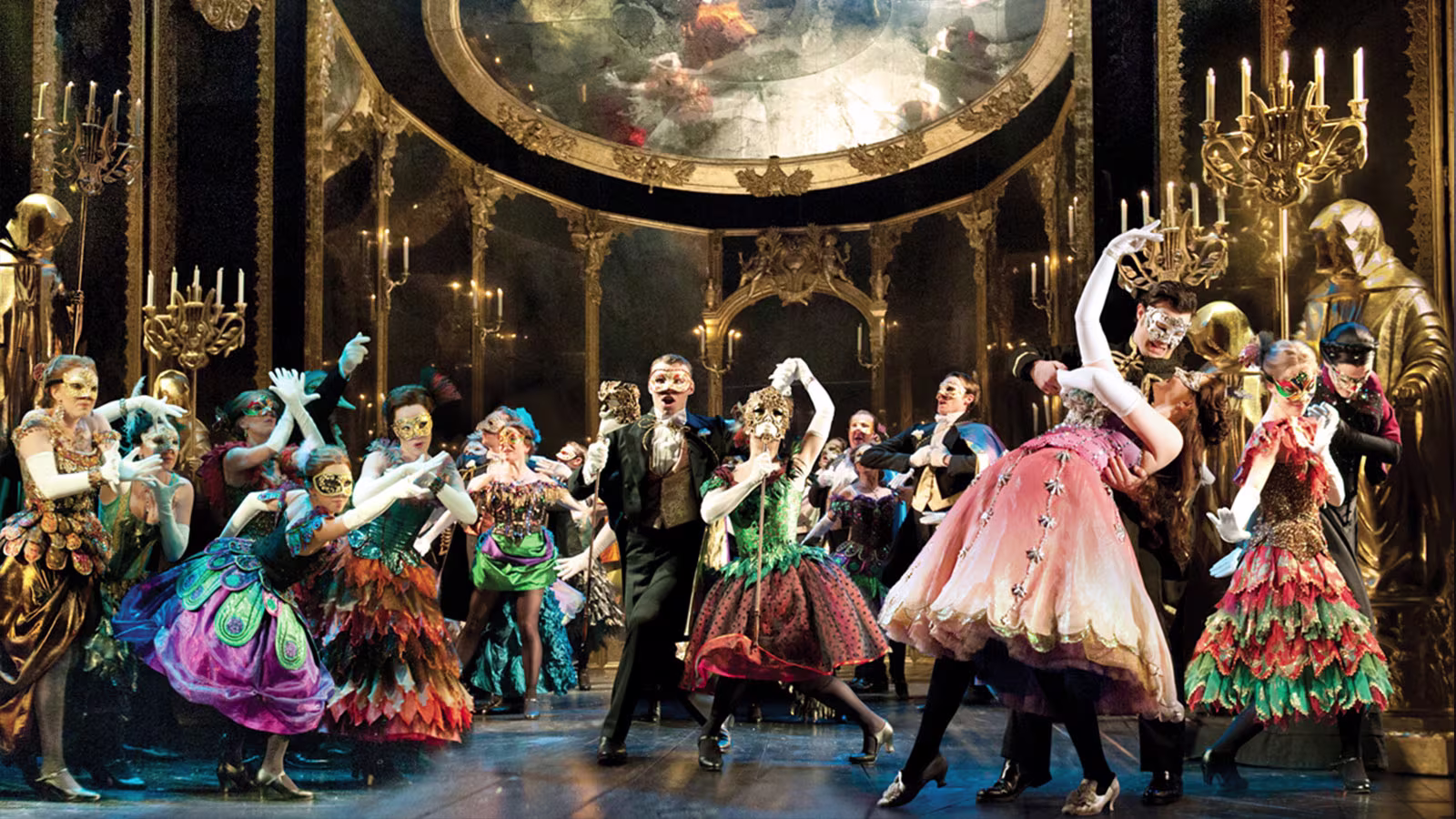 Das Phantom der Oper Maskenball-Tanzszene mit mehreren Darstellern in Barocker Kleidung und Gesichtsmasken.