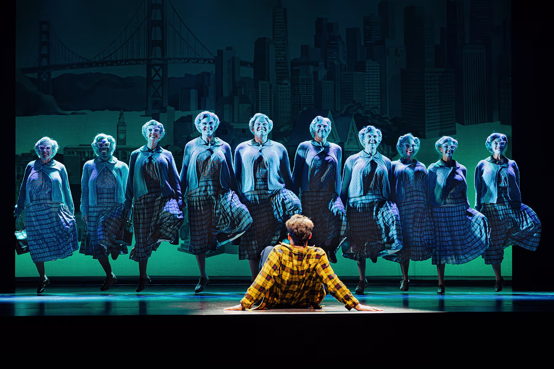 Eine Bühnenszene von Mrs Doubtfire – Der neue Musical-Hit: Zehns verschiedene Mrs Doubtfires tanzen mit schottischen Röcken.