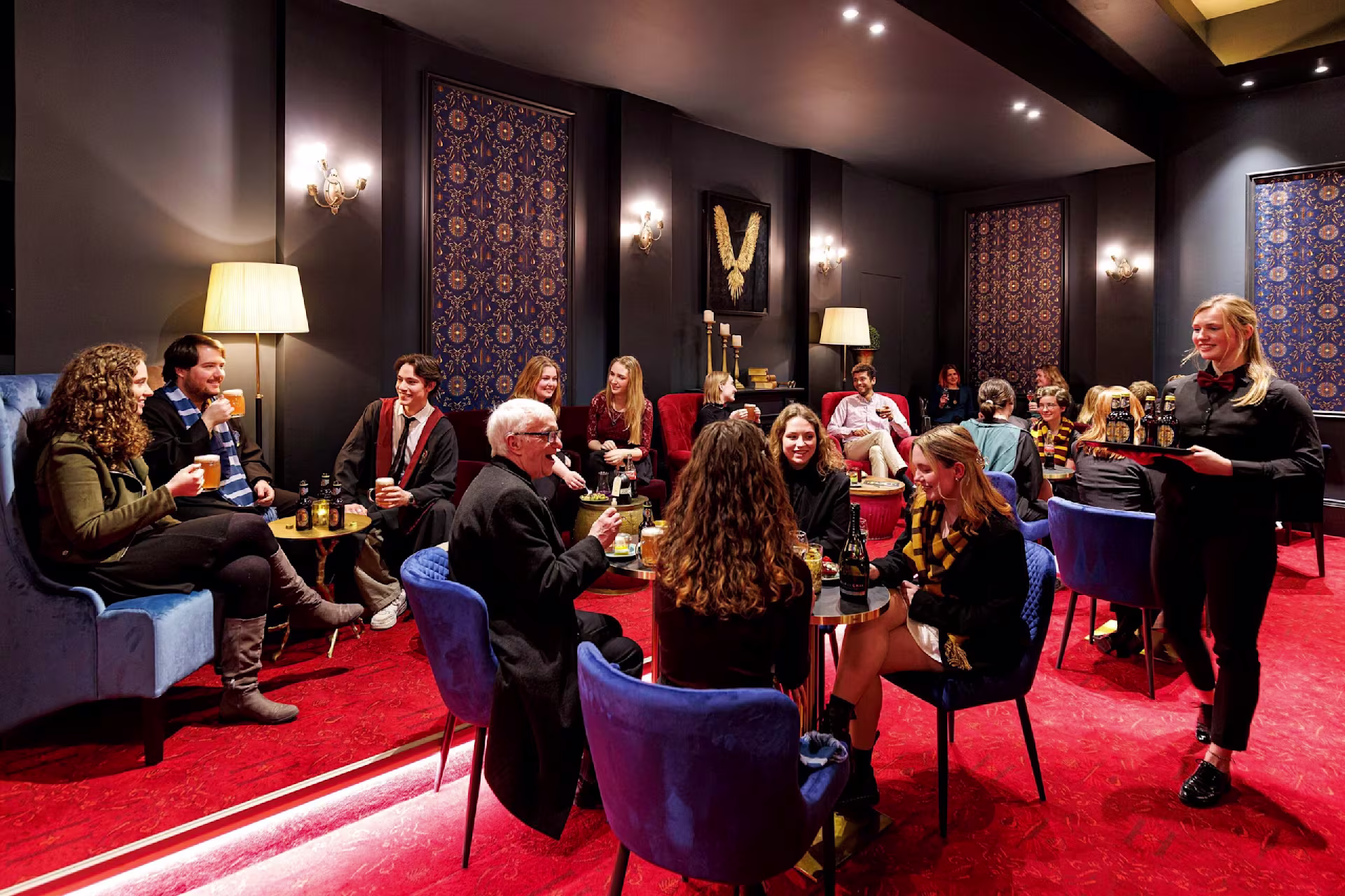 Besucher*innen die an Tischen im Foyer sitzen 
