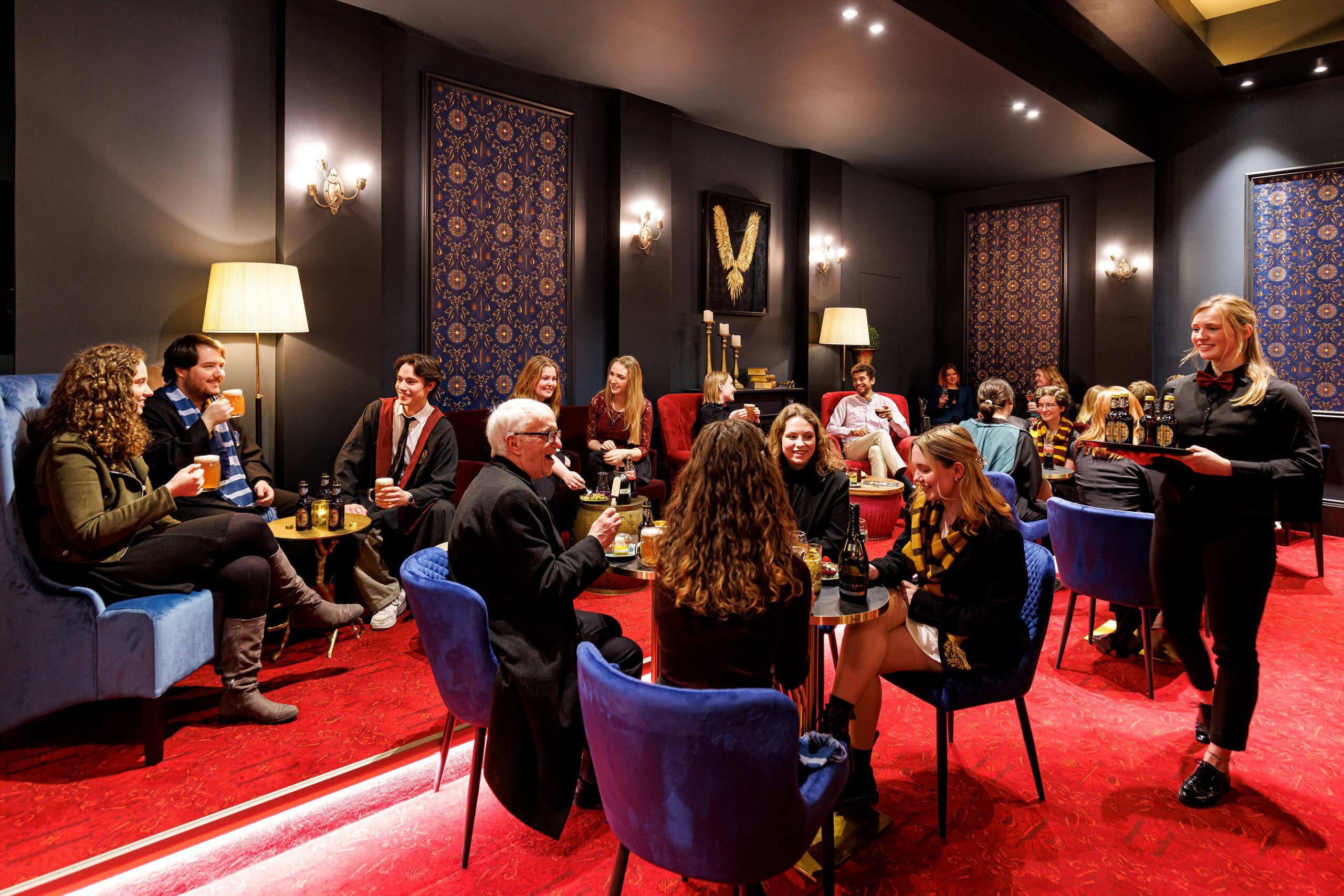 Besucher*innen die an Tischen im Foyer sitzen 