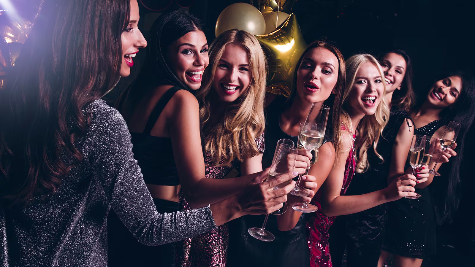 Freundinnen stoßen beim Mädelsabend im Club mit Sektgläsern an
