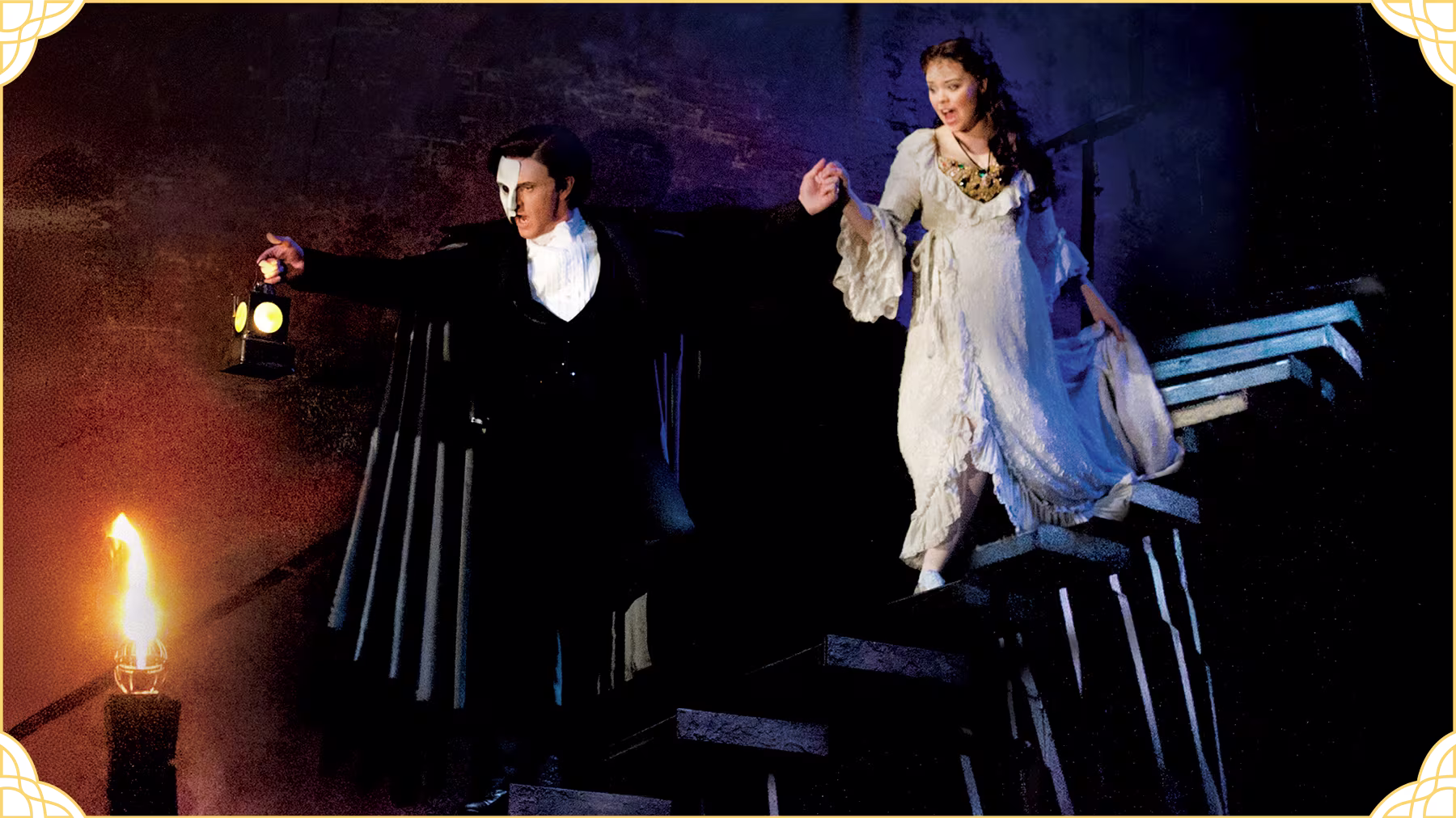 Das Phantom der Oper - Mann mit Maske und Anzug führt Frau mit weißem Kleid die Treppe herunter