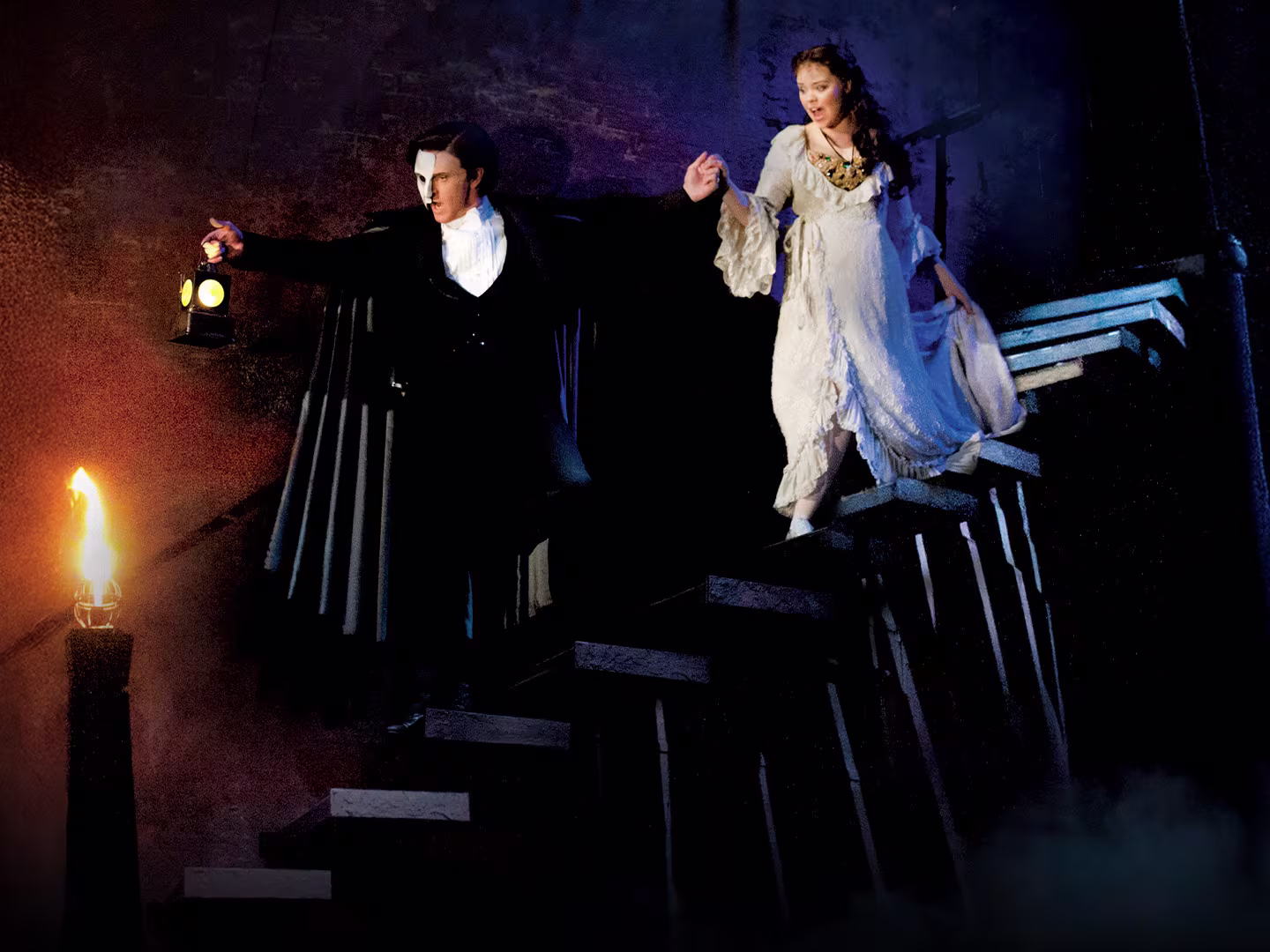 Das Phantom der Oper - Mann mit Maske führt frau in weißem Kleid die Treppe herunter