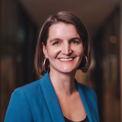 Portrait von Frau mit braunen Haaren, Ohrringen und einem blauen Blazer