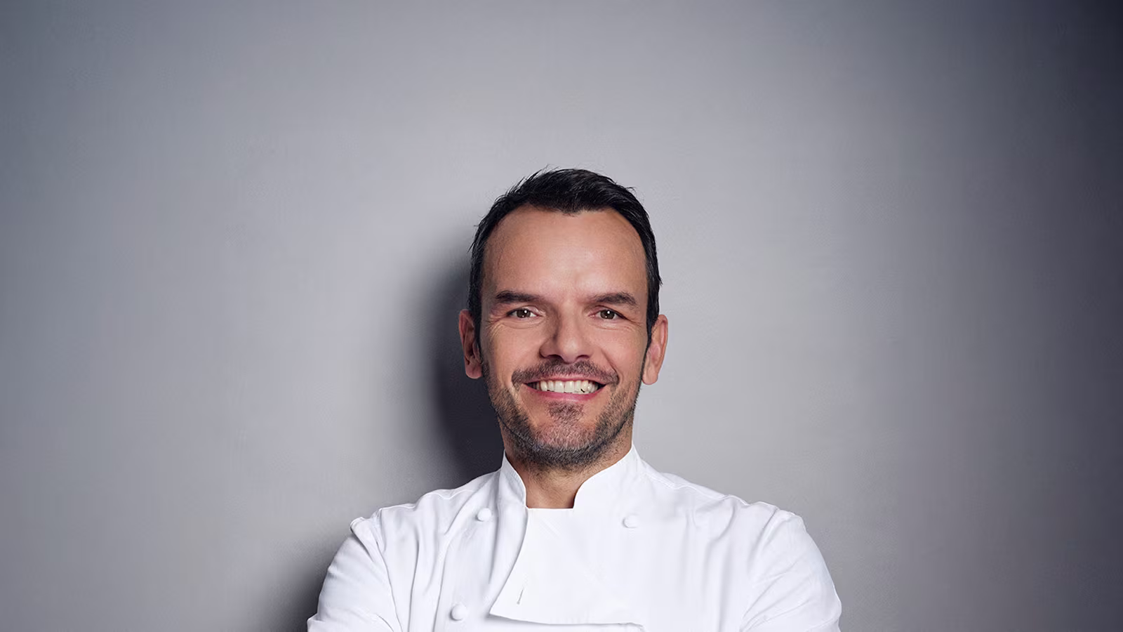 Steffen Henssler Gesicht nah vor grauer Wand