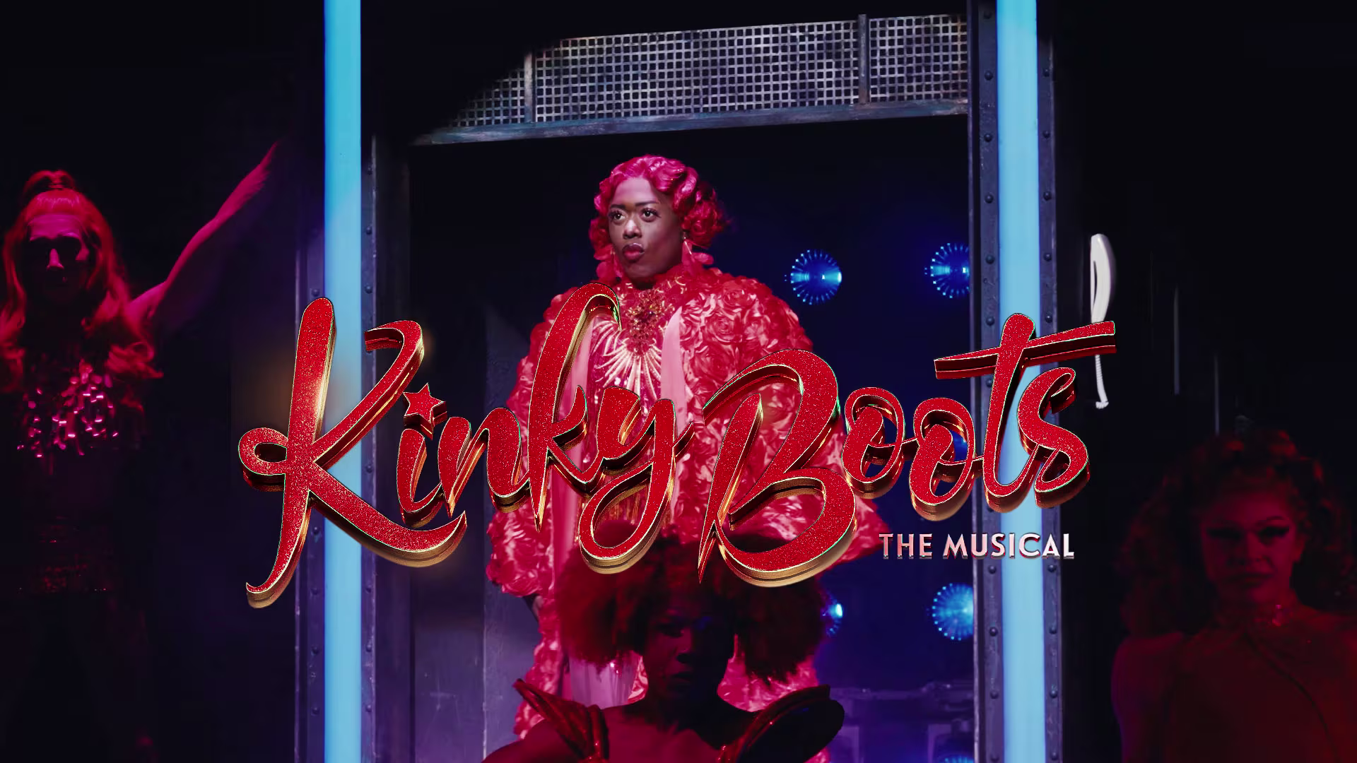 Titel von "Kinky Boots – The Musical" vor Bühnen-Hintergrund mit Darsteller