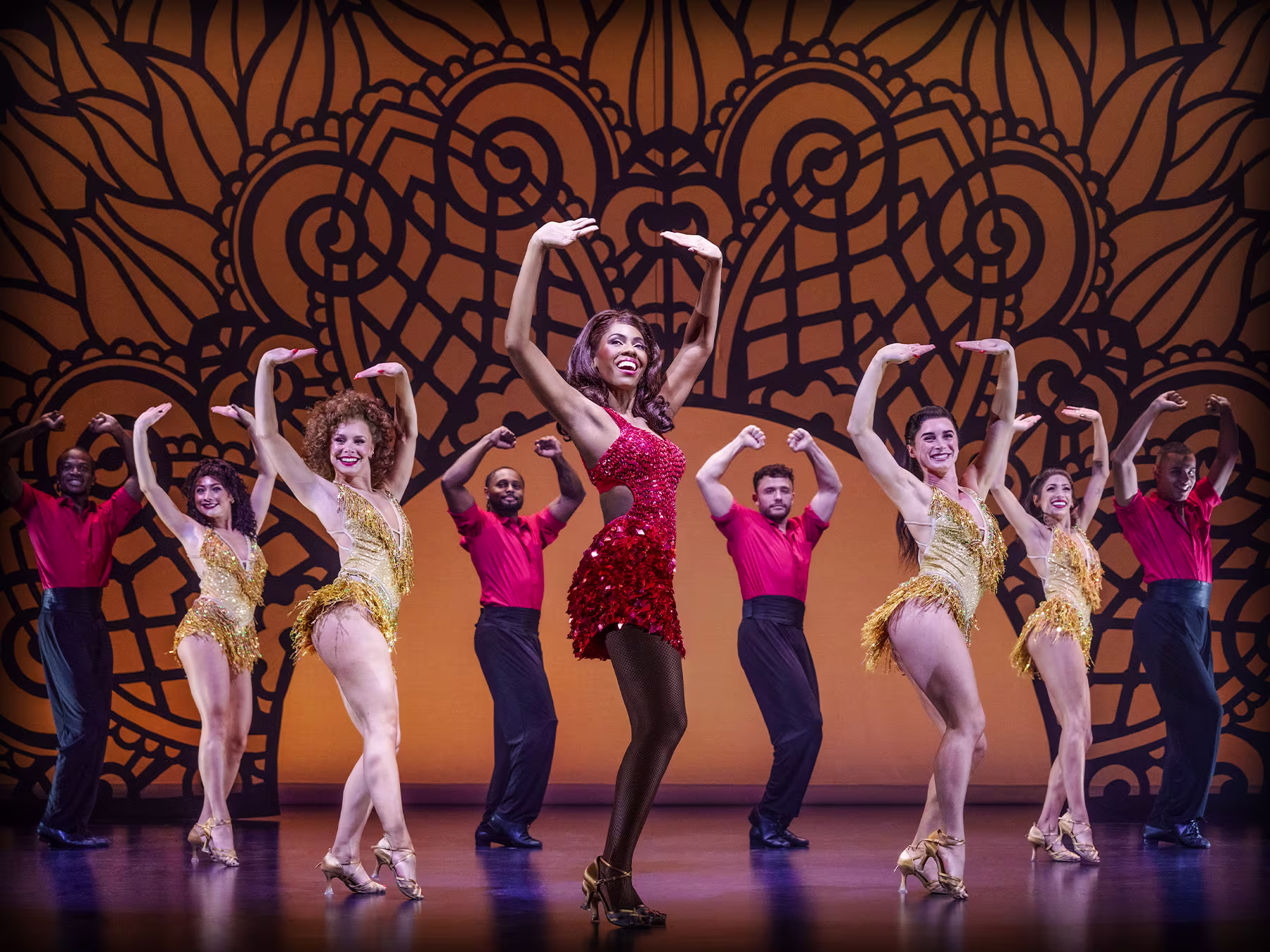 "The Bodyguard – The Musical": auf der Bühne stehen neun Personen in rot-schwarzen und goldenen Kostümen und tanzen
 