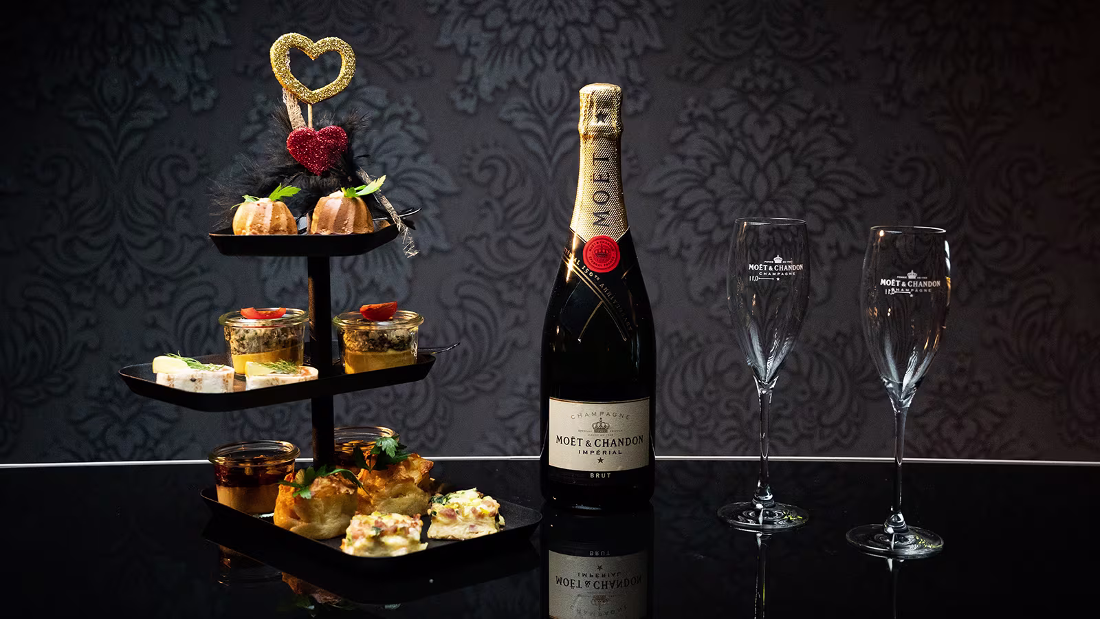 Etagere mit einer Auswahl von verschieden Fingerfood- Snacks, zudem eine Champagner-Flasche mit entsprechenden Gläsern 