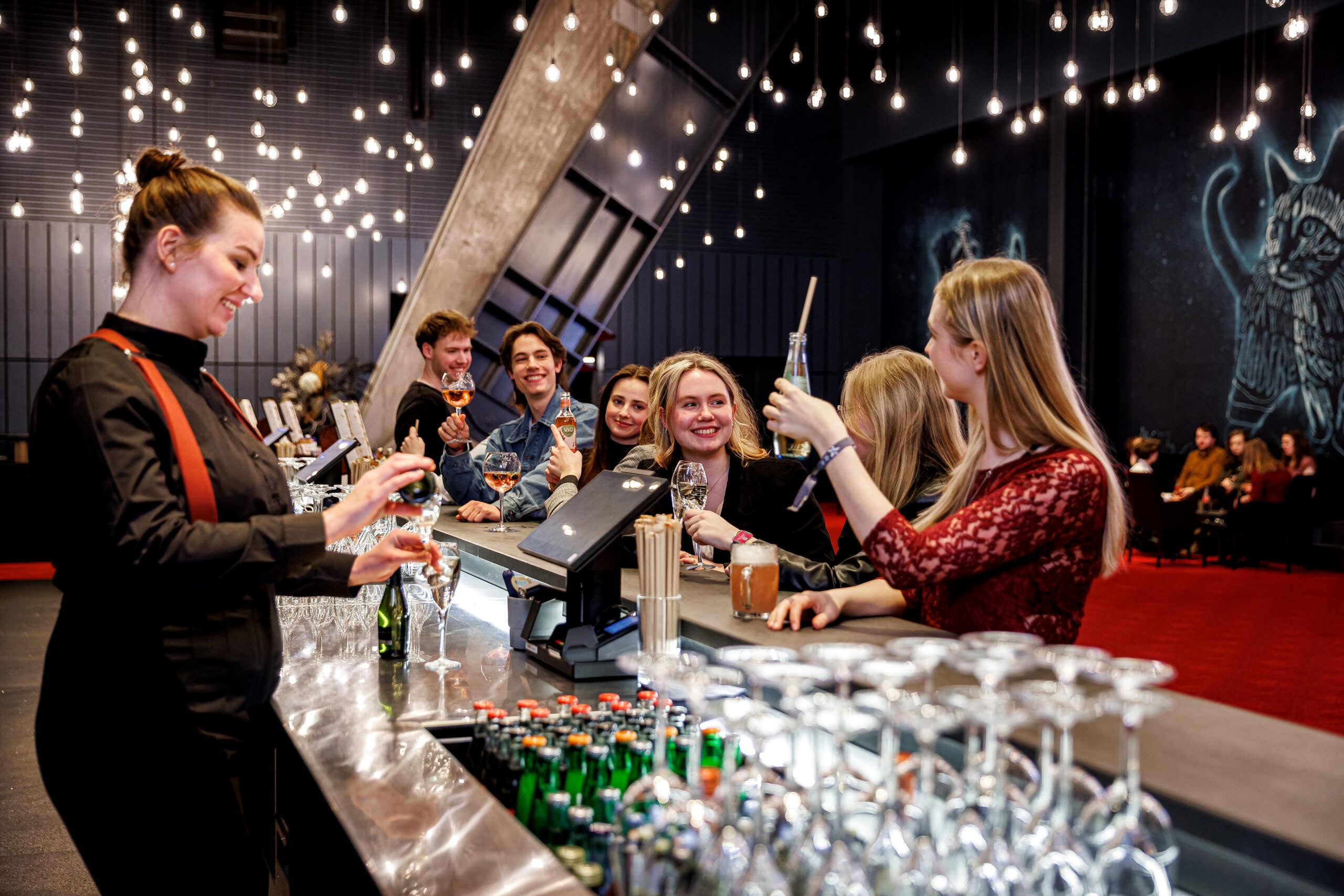 Besucher*innen mit Getränken an der Bar 