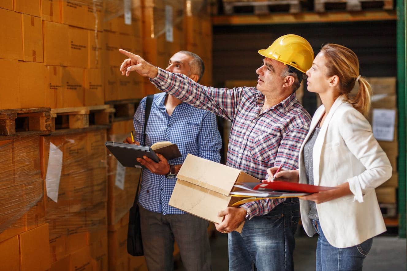 three people in warehouse one in yellow hard hat