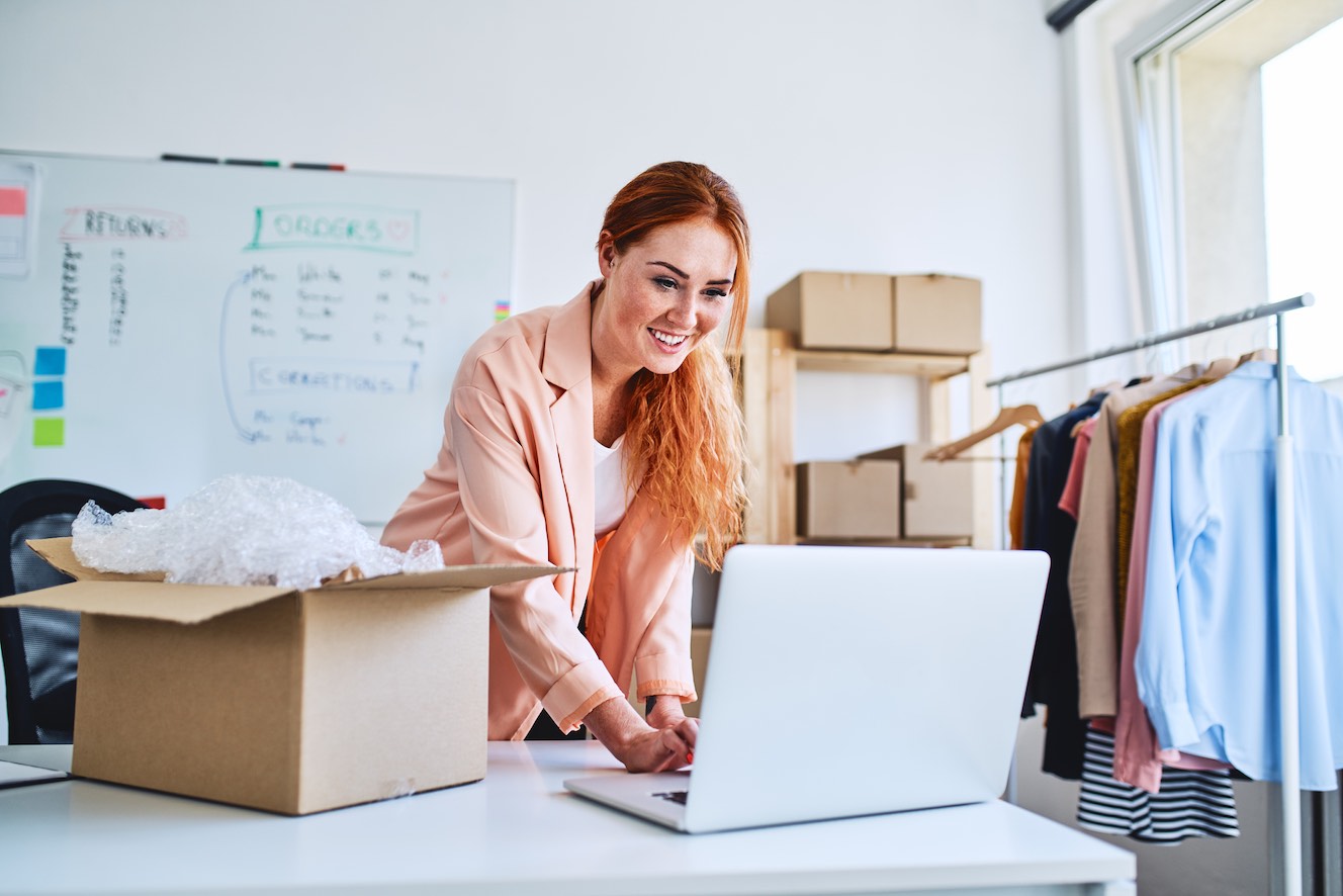 Woman packing a box and choosing a shipping method on her computer. 