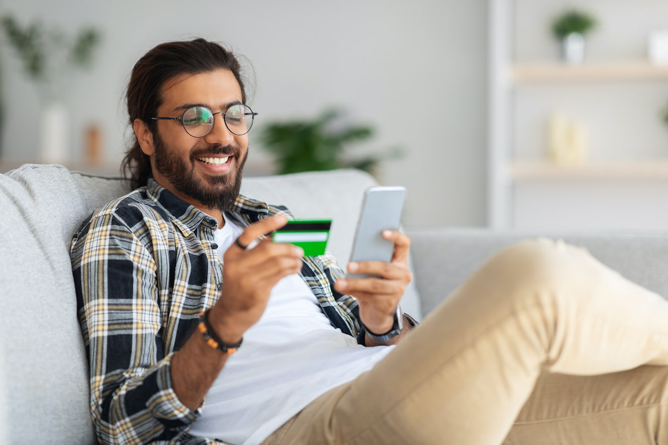 man on couch reading credit card info