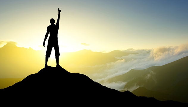 Person standing on a mountain giving a thumbs up