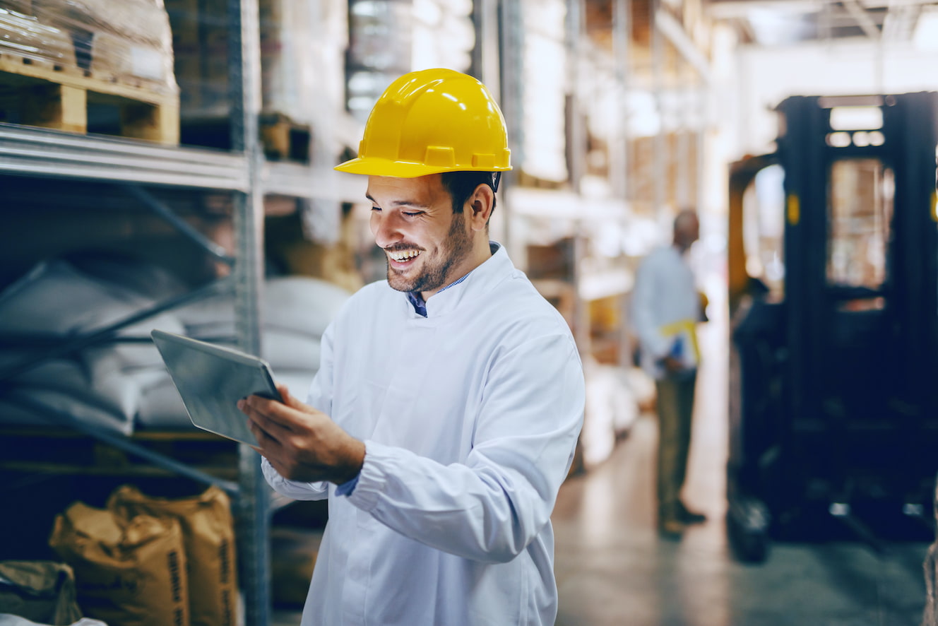 Man wearing hardhat looking at tablet in warehouse