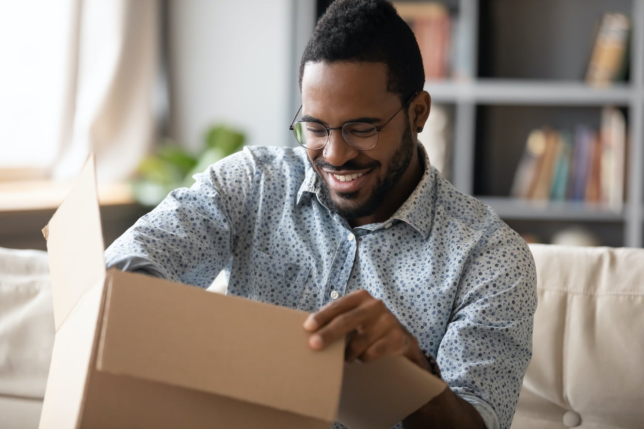 Man smiling while opening a package
