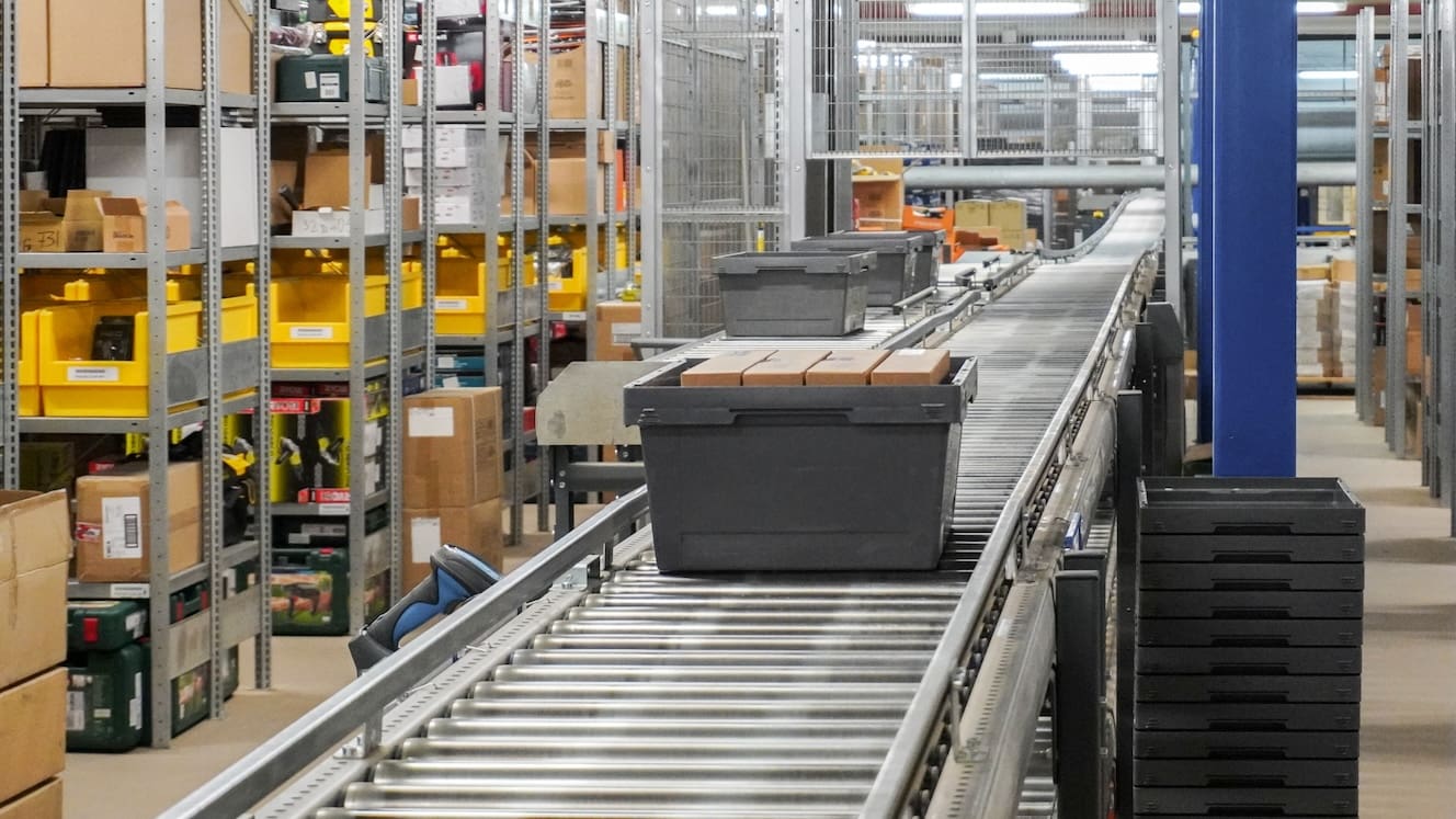 A bin filled with small parcels on a conveyor belt in a fulfillment center
