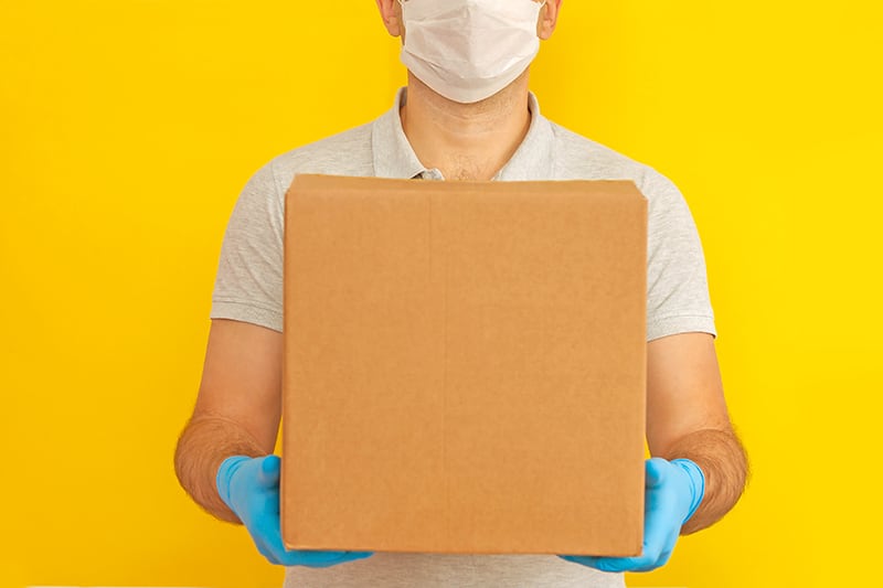 person with mask on holding package
