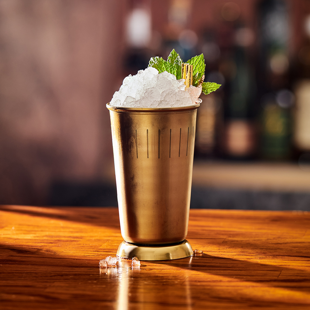 A golden cup filled with crushed ice sits on a polished wooden surface.