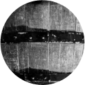 A black and white circular image showing a close-up of a wooden barrel.