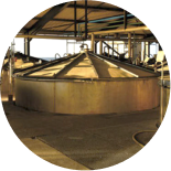 A large, circular metal vat with a conical top inside an industrial facility.