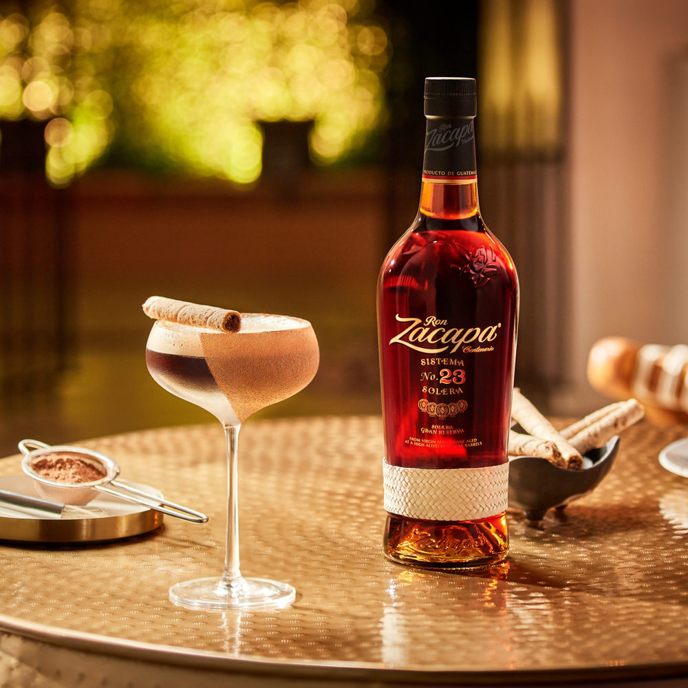 A coupe glass filled with a creamy Ron Zacapa rum cocktail, garnished with a rolled wafer.