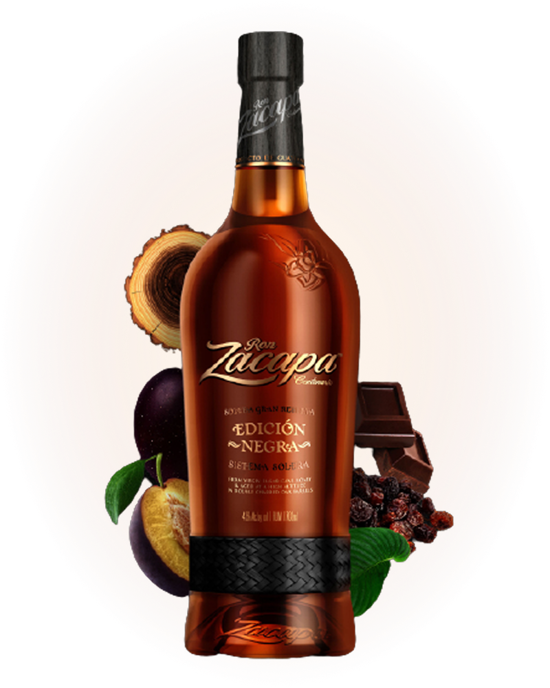 A bottle of Ron Zacapa Edición Negra rum is centered in the image, surrounded by ingredients like dark chocolate, dried fruit, and sliced wood.