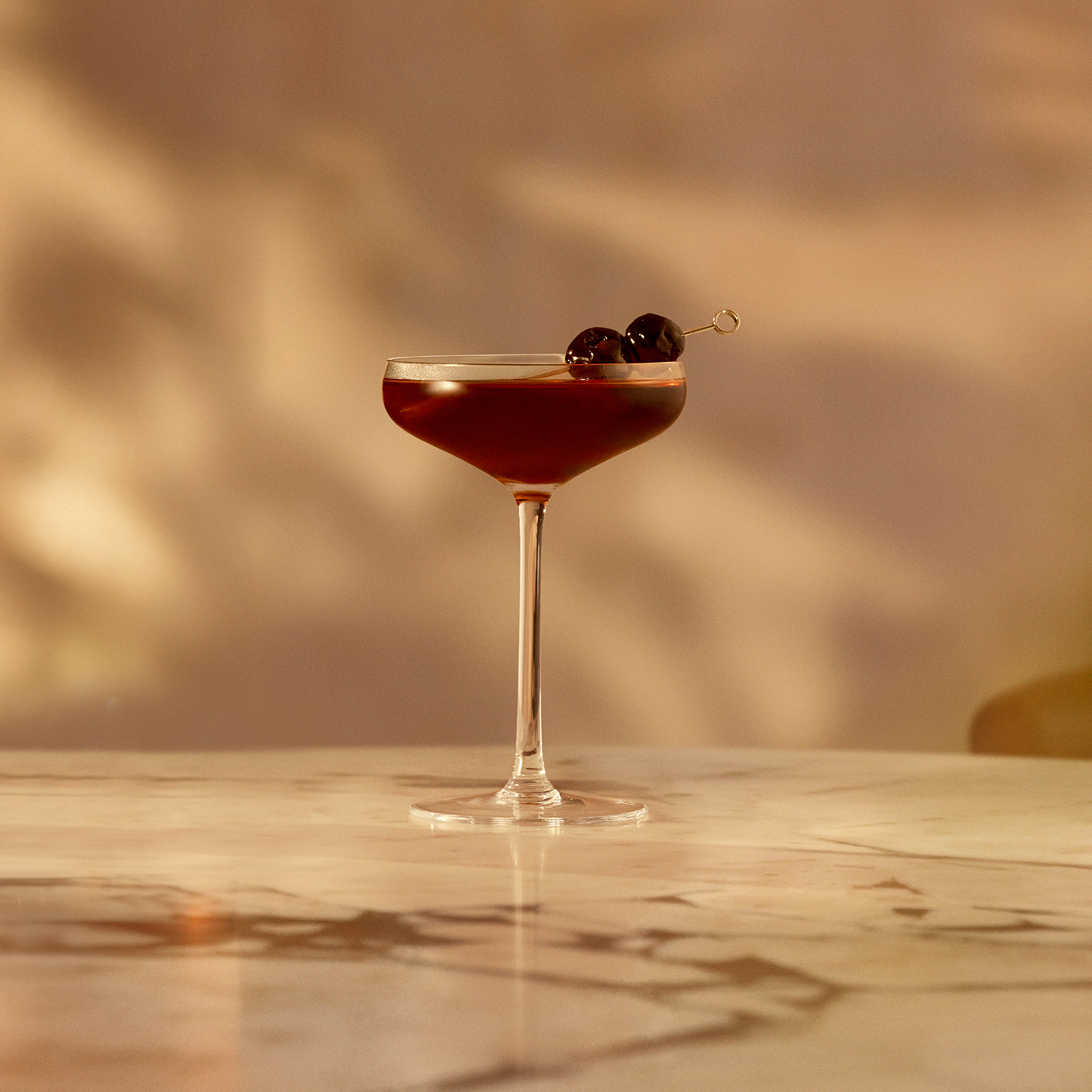 A coupe glass filled with a deep red cocktail is elegantly presented on a marble surface.