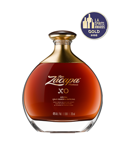 A bottle of Ron Zacapa XO rum is centered against a dark background.