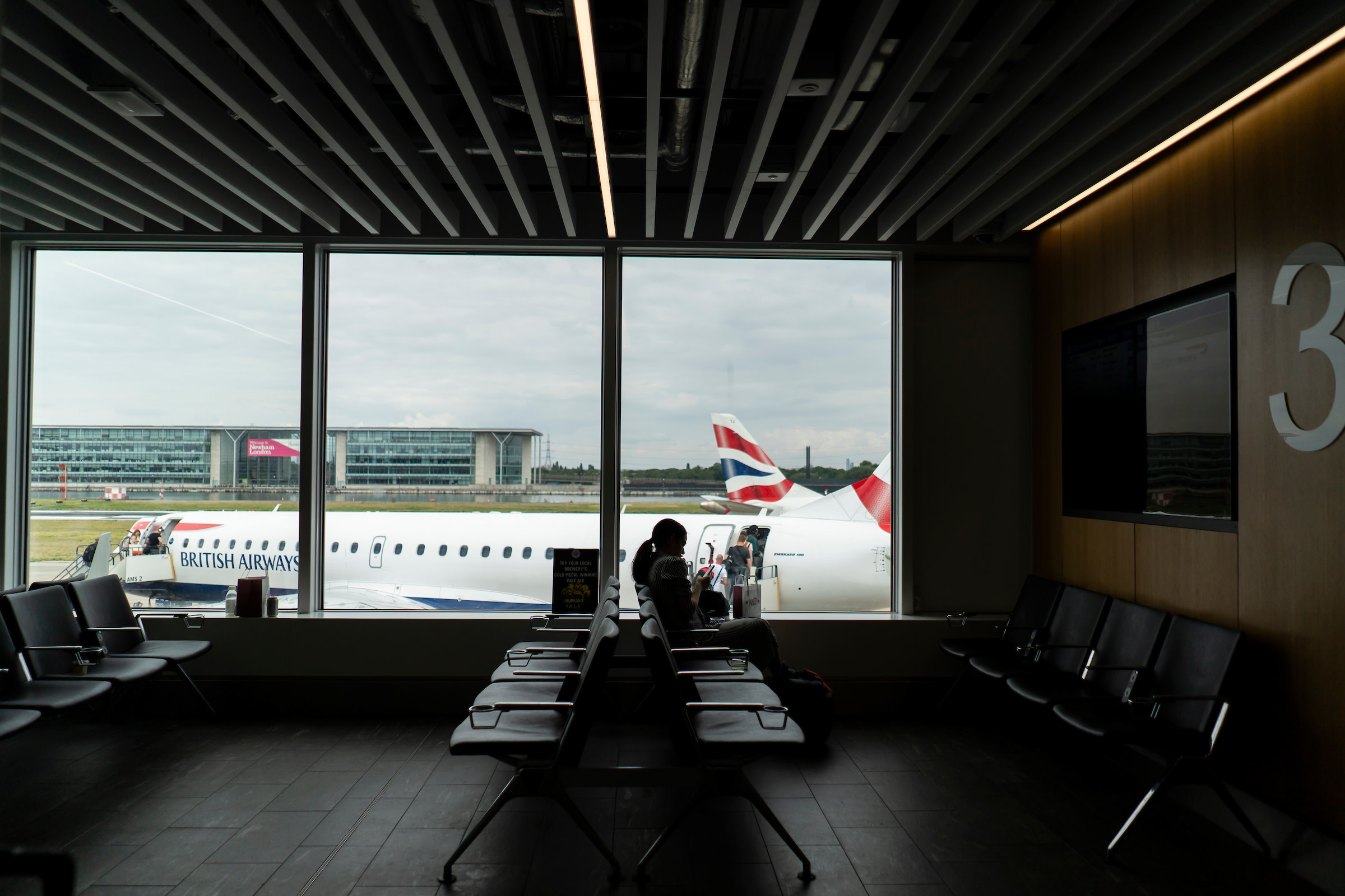 Lady in waiting area of LCY airport with British Airways plane in the background