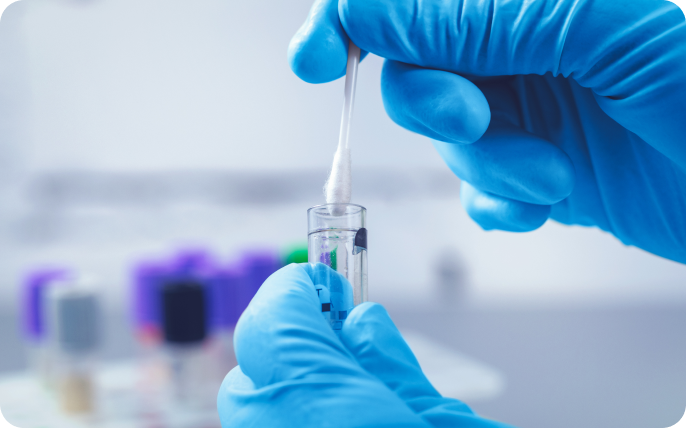 Gloved hand placing swab sample in a tube.