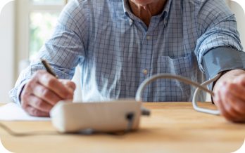 Older man checking his blood pressure with a cuff and digital monitor.