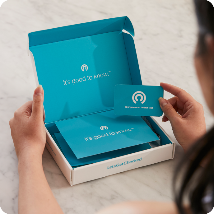 Close up of someone's hands opening a LetsGetChecked testing kit.