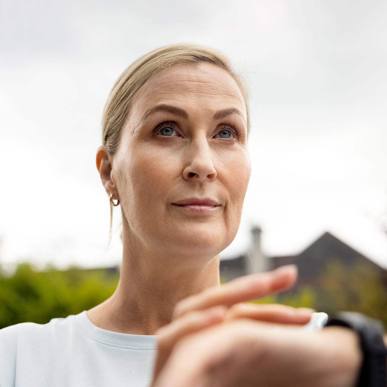 Portrait of a woman outdoors, attentively checking her smartwatch.