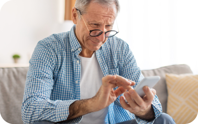 Older man using his smartphone from the comfort of his home.