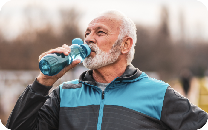 Older man drinking water from a bottle outdoors.