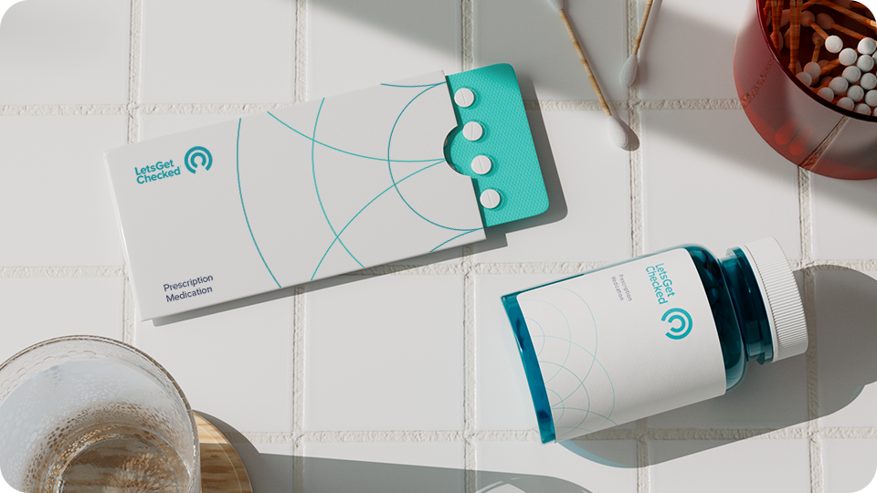 LetsGetChecked branded pack of tablets, and pill bottle on a tiled surface. LetsGetChecked branded pack of tablets, and pill bottle on a tiled surface.