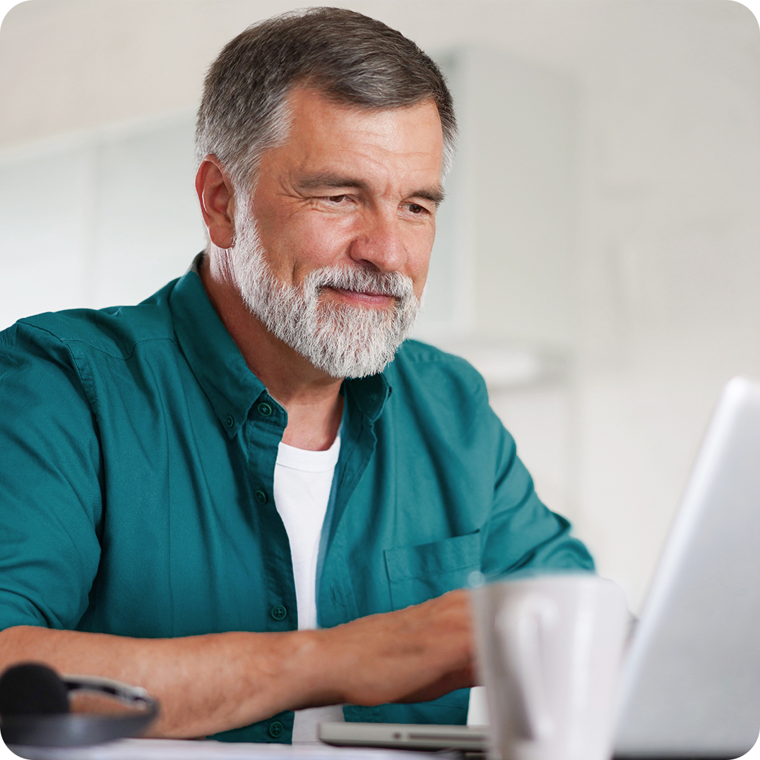 Smiling older man using a laptop at home.