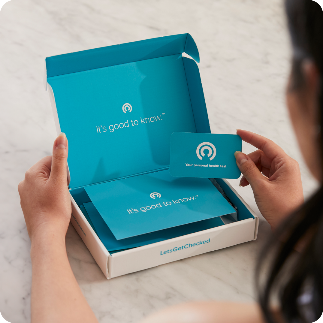 Close up of someone's hands opening a LetsGetChecked testing kit.