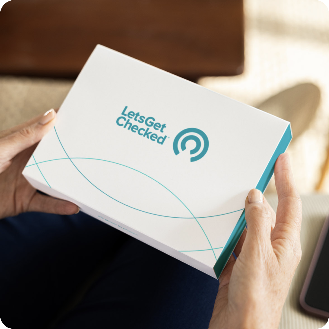 Close up of hands holding a LetsGetChecked test kit.